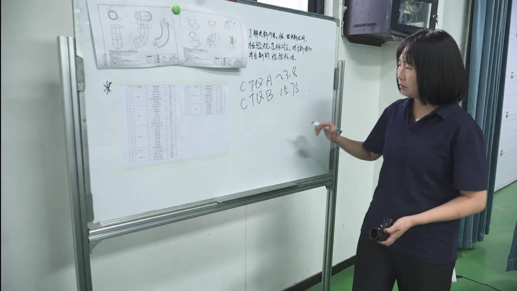 Technical staff reviewing rubber component drawings and specifications on a whiteboard.