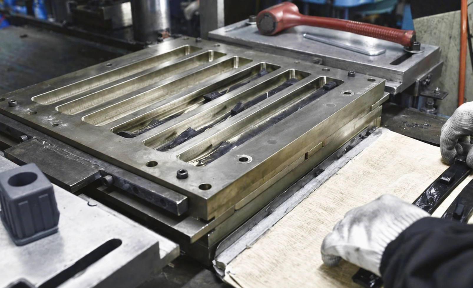 Industrial steel rubber molding tool with a worker handling materials during the manufacturing preparation process.